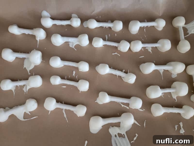 White chocolate pretzel bones setting on parchment paper, freshly dipped and ready to harden