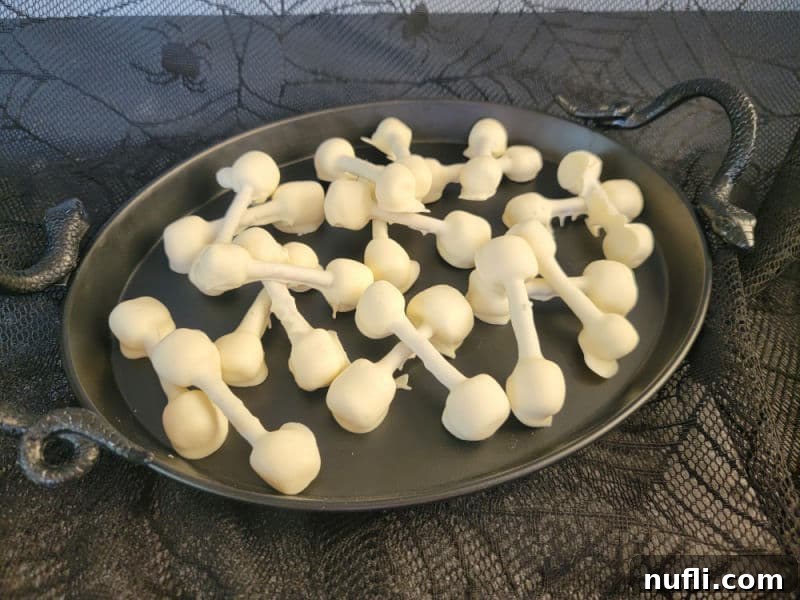 Almond bark pretzel bones arranged on a sleek black platter, ready for a Halloween gathering
