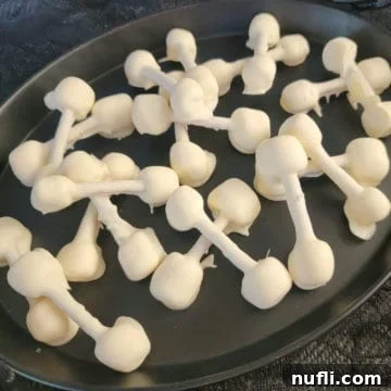 Halloween Pretzel Bones covered in white chocolate on a black platter