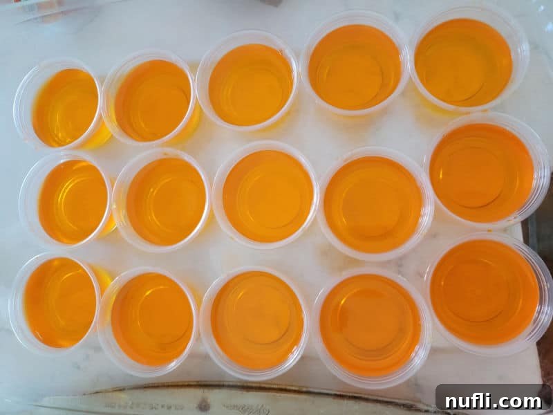 Festive Candy Corn Jello Shooters 5 Orange Jello in plastic jello shot cups in a baking dish