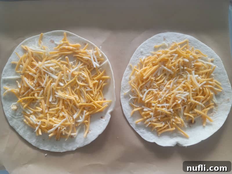 shredded cheese on tortillas on parchment paper