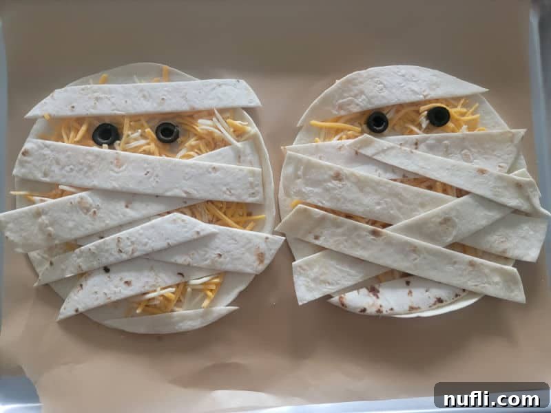 Mummy Quesadillas on parchment paper before baking