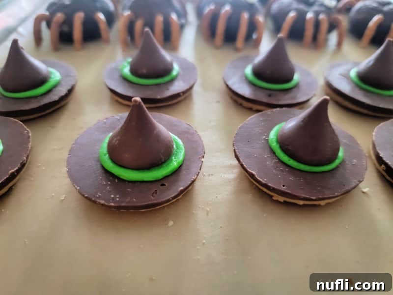 Green-rimmed witch hat cookies resting on parchment paper after assembly
