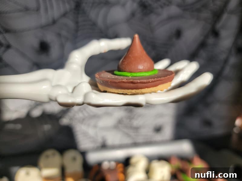 Witch hat cookie held by a skeleton hand, emphasizing the Halloween theme