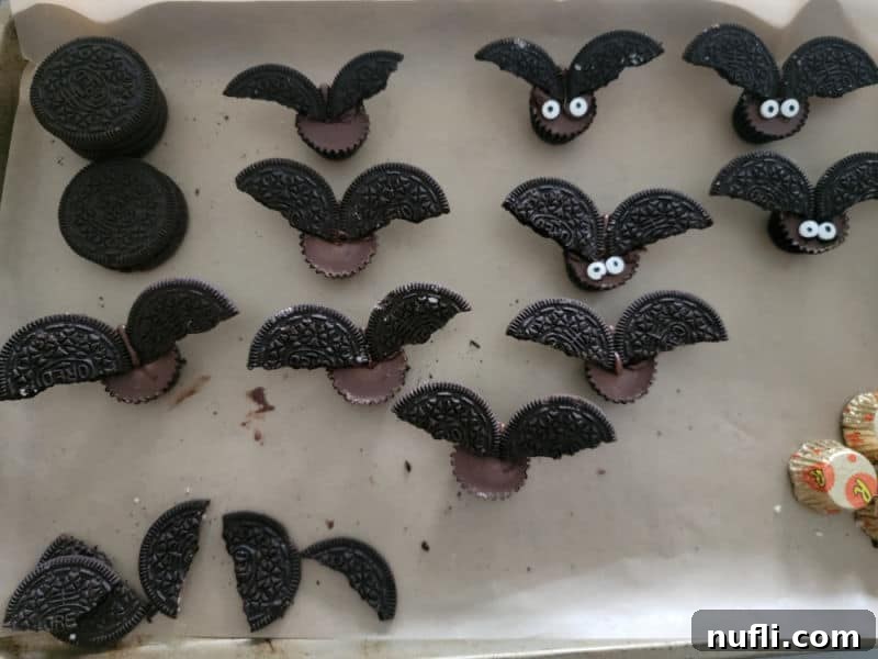 Partially assembled Reese's Bats showing Oreo wings attached to peanut butter cups, with candy eyes ready to be added.