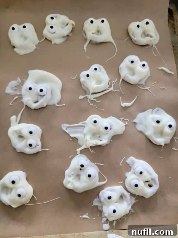 ghosts pretzels with candy eyes on parchment paper