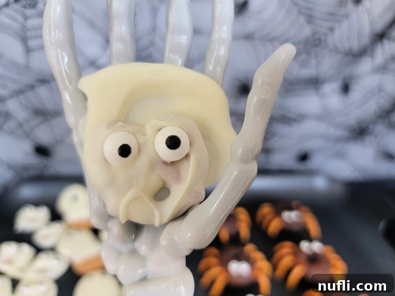 Ghost pretzels with candy eyes held on a skeleton hand