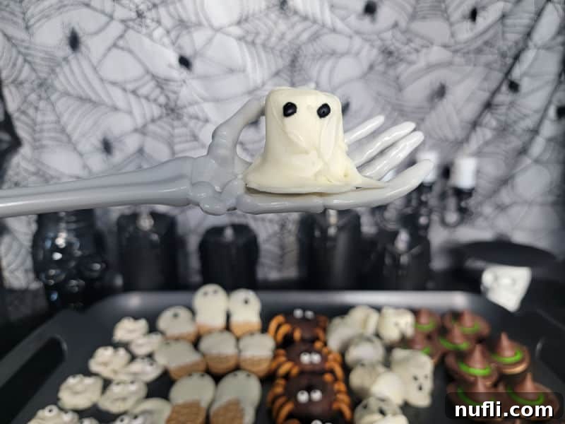 marshmallow ghost on a skeleton hand over a platter of halloween treats