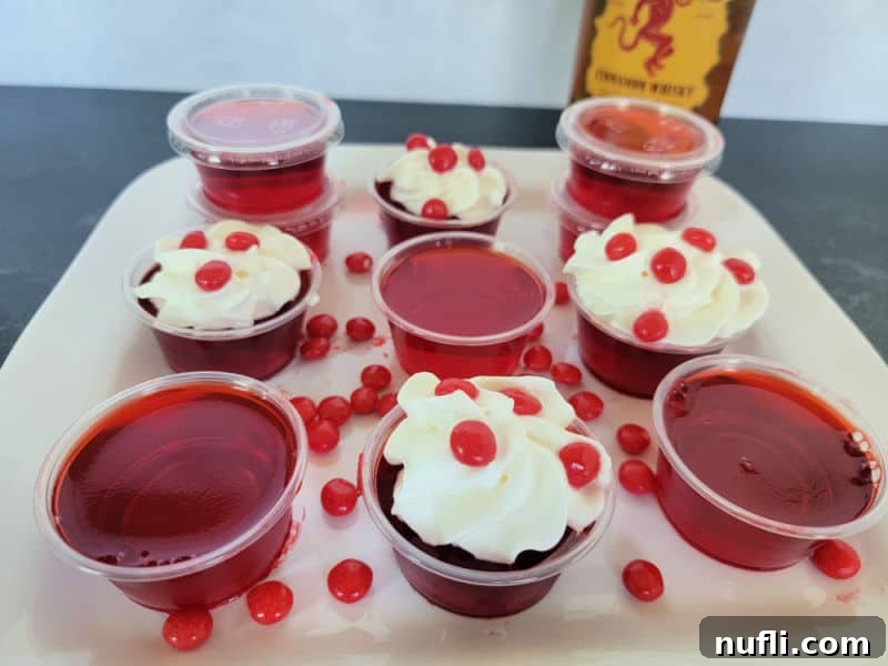 Inferno Jiggle Shots 8 Fireball Jello Shots in plastic cups some garnished with whipped cream and red hots with a bottle of Fireball Cinnamon Whiskey