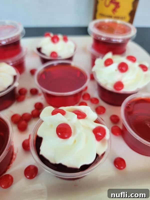 Inferno Jiggle Shots 9 Fireball red jello shots in plastic cups garnished with whipped cream and red hots