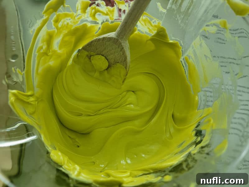 Festive Grinch Bark Made Easy 4 Green candy melt melted in a bowl with a wooden spoon.