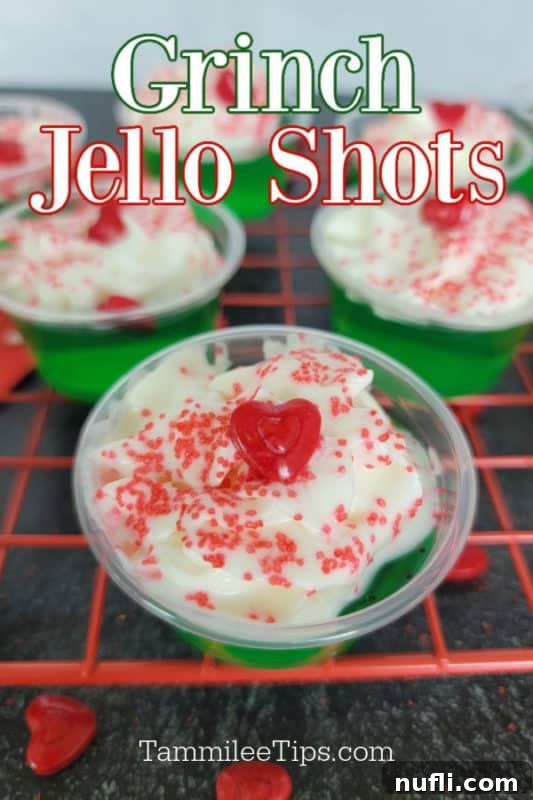 Deliciously Easy Festive Grinch Jello Shots 2 Vibrant green Grinch Jello Shots topped with whipped cream, a red heart candy, and festive sprinkles, ready for a Christmas party