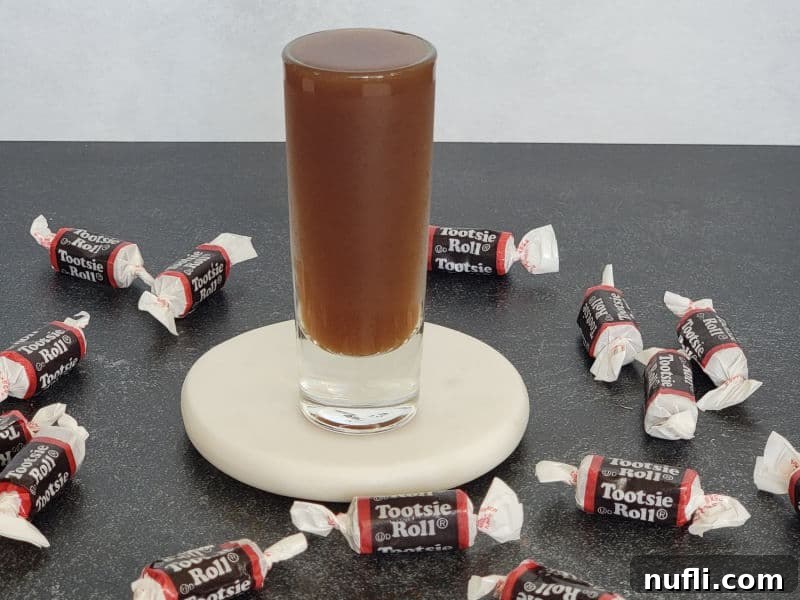 Tootsie Roll Shot on a white coaster surrounded by Tootsie Roll candy