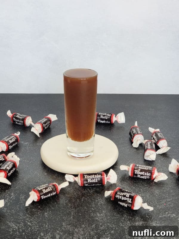 Tootsie Roll Shot on a white coaster surrounded by Tootsie Roll candies