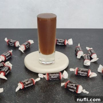 Tootsie Roll Shot on a white coaster surrounded by Tootsie Roll Candies