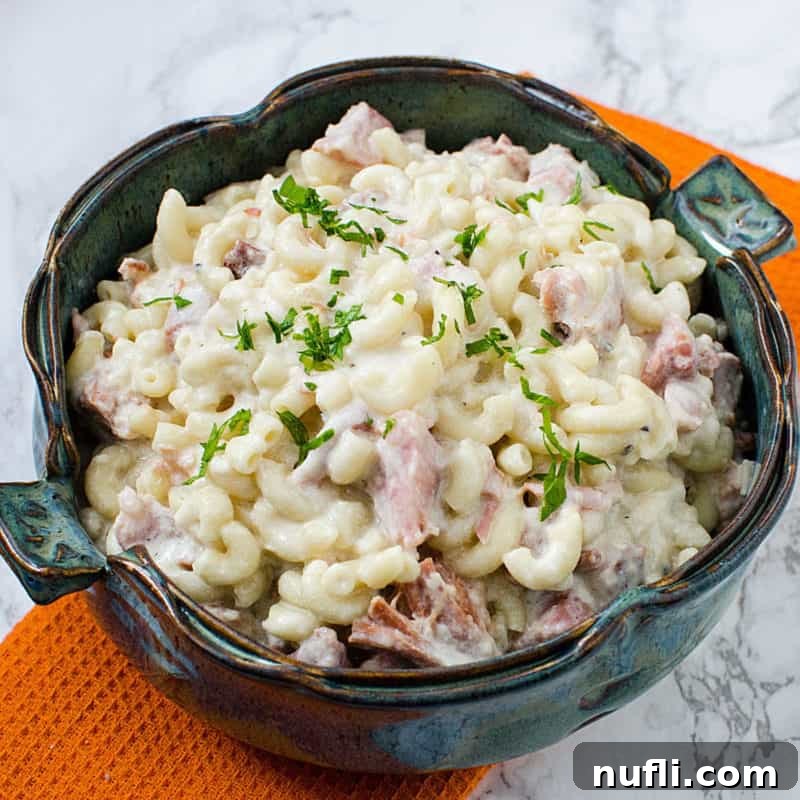 Macaroni and Cheese with ham in a clay bowl on a orange napkin
