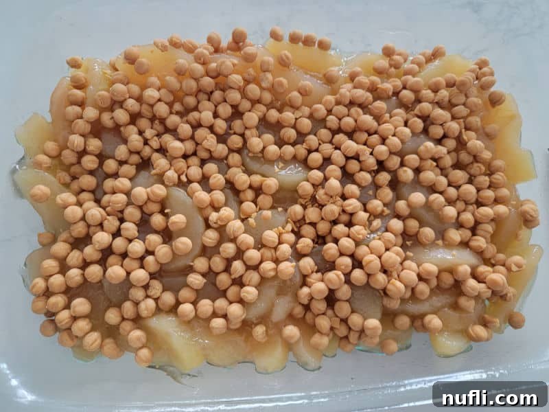 Caramel bits generously and evenly sprinkled over the smooth layer of apple pie filling in a glass baking dish, ready for the next layer.