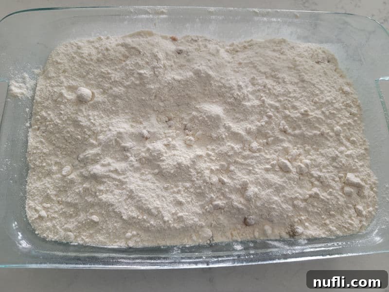 Dry yellow cake mix carefully spread in an even layer over the caramel bits and apple mixture in a glass baking dish, forming the dry cake topping.