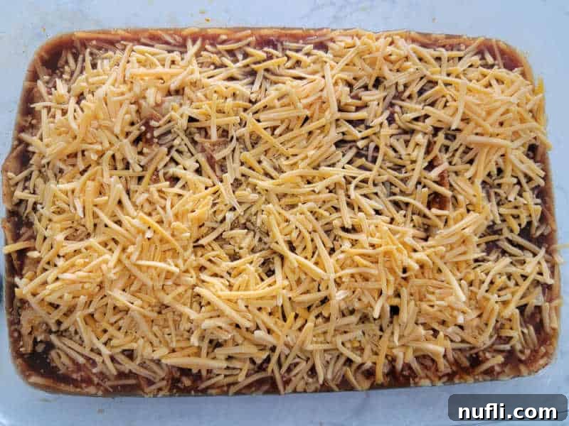 Shredded cheese spread over taquito enchiladas