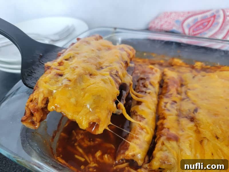 Cheezy lazy enchiladas scooping out of a glass casserole pan