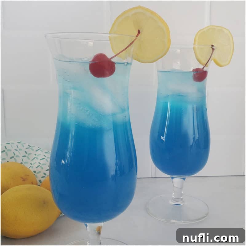 Blue Lagoon Cocktail in Hurricane glasses with lemon wheel and cherry