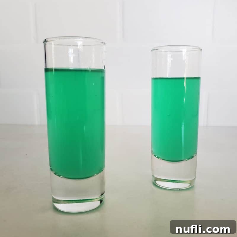 Two green cocktail shots in tall shot glasses