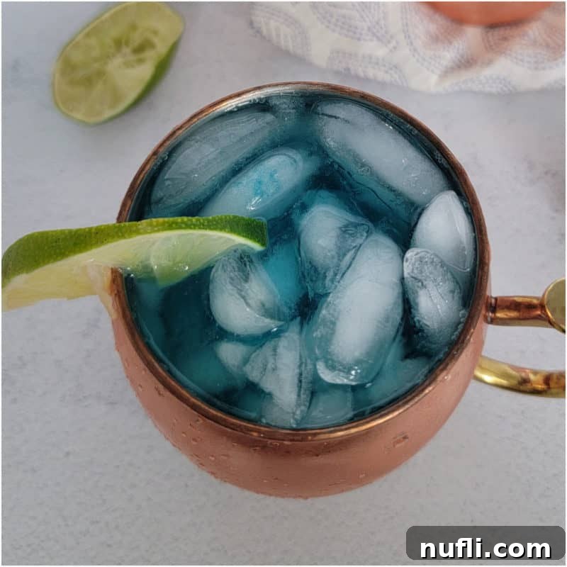 Blue mule in a copper mug with a lime wedge and limes nearby