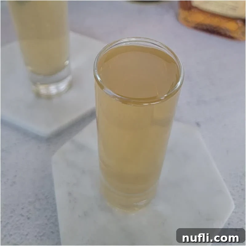 The Ultimate Guide to Peach Schnapps Cocktails 12 tan colored shot in a shot glass on a white coaster