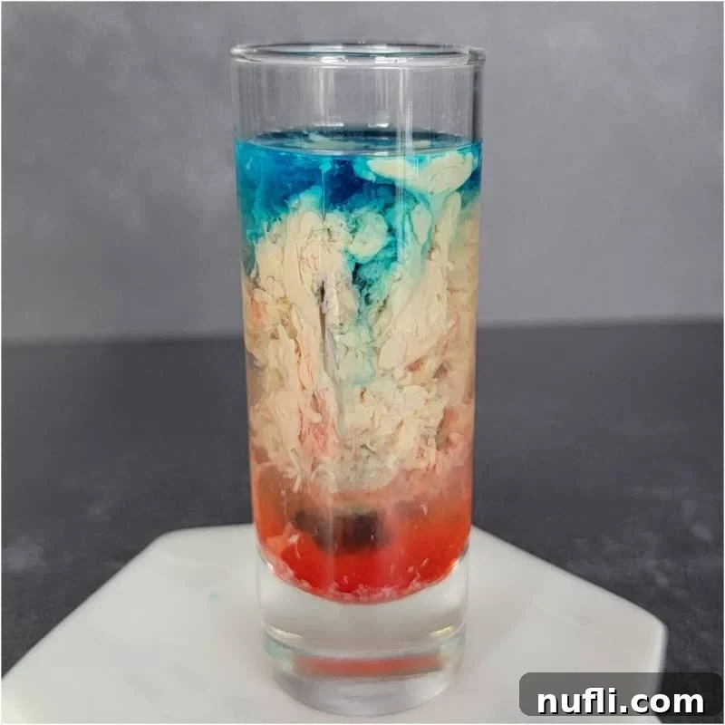 The Ultimate Guide to Peach Schnapps Cocktails 13 Blue Cream and Red alien brain hemorrhage shot in a clear glass on a white coaster.