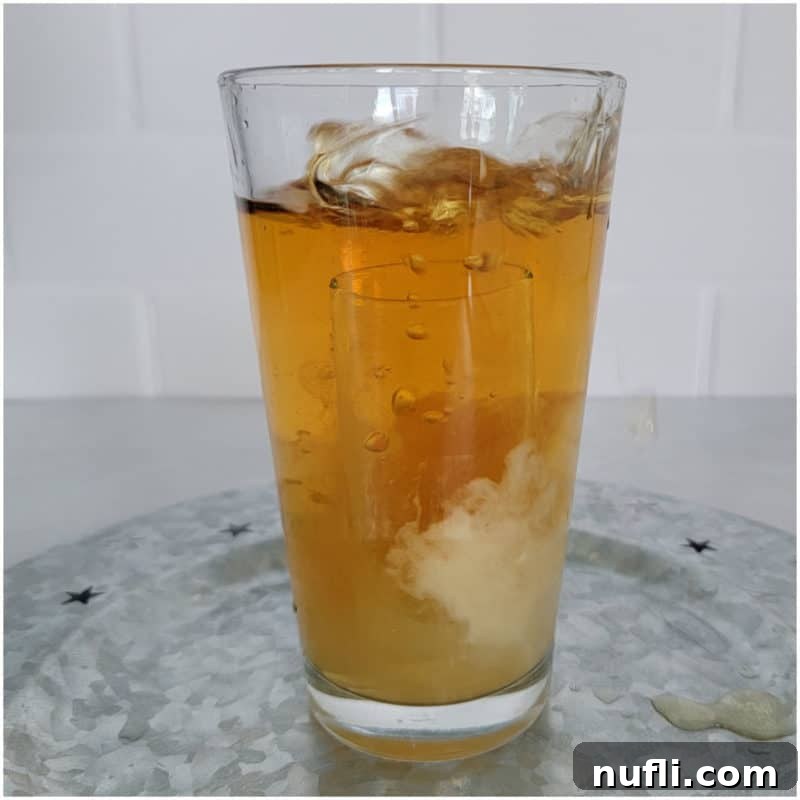 The Ultimate Guide to Peach Schnapps Cocktails 17 Glass shot dropping into a tall glass with brown orange liquid