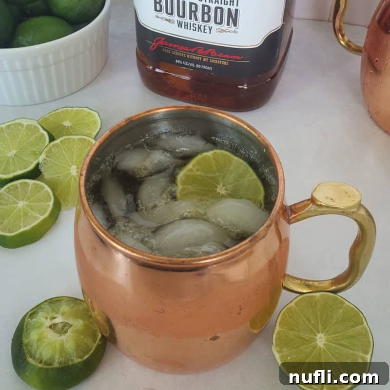 Mastering Ginger Beer Mixology 5 Kentucky Mule with lime circles in a copper mug next to a bottle of kentucky bourbon