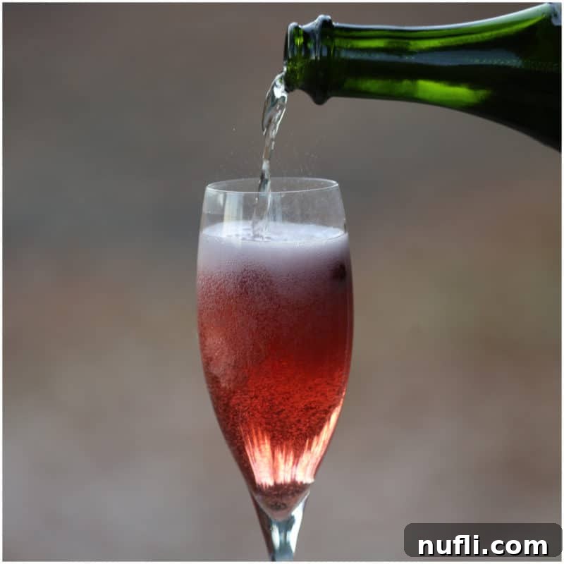 green champagne bottle pouring into a champagne flute with cranberry mimosa