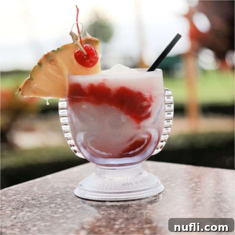 red and white lava flow cocktail in a tiki glass with pineapple wedge and cherry garnish
