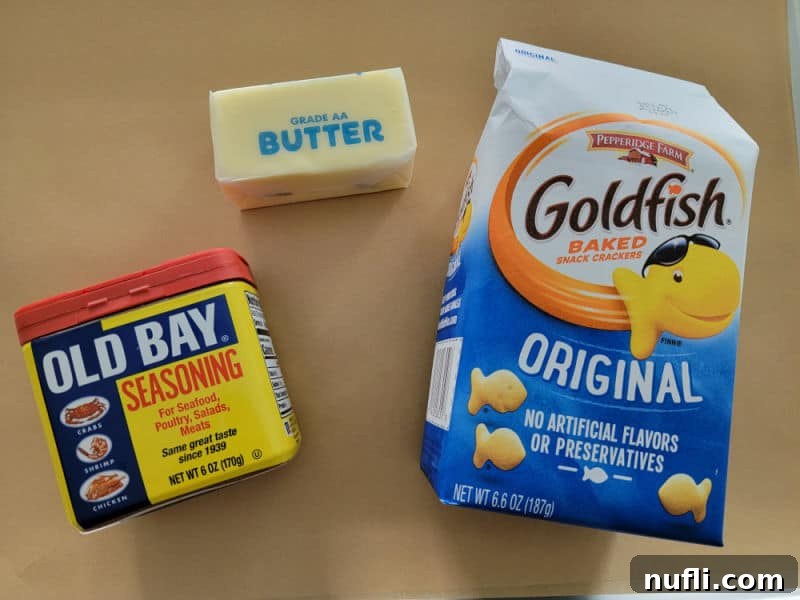 Old Bay Goldfish Cracker ingredients butter, goldfish crackers, and Old Bay seasoning on a piece of parchment paper