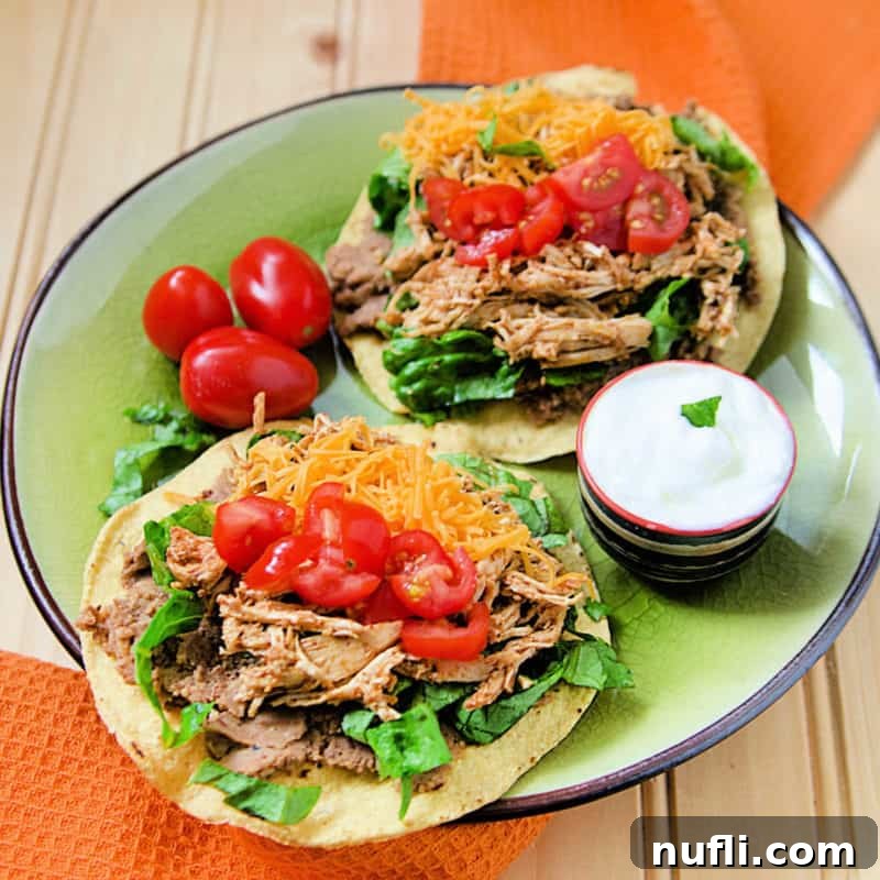 Vibrant chicken tostadas topped with cheese and fresh tomatoes on a green plate.