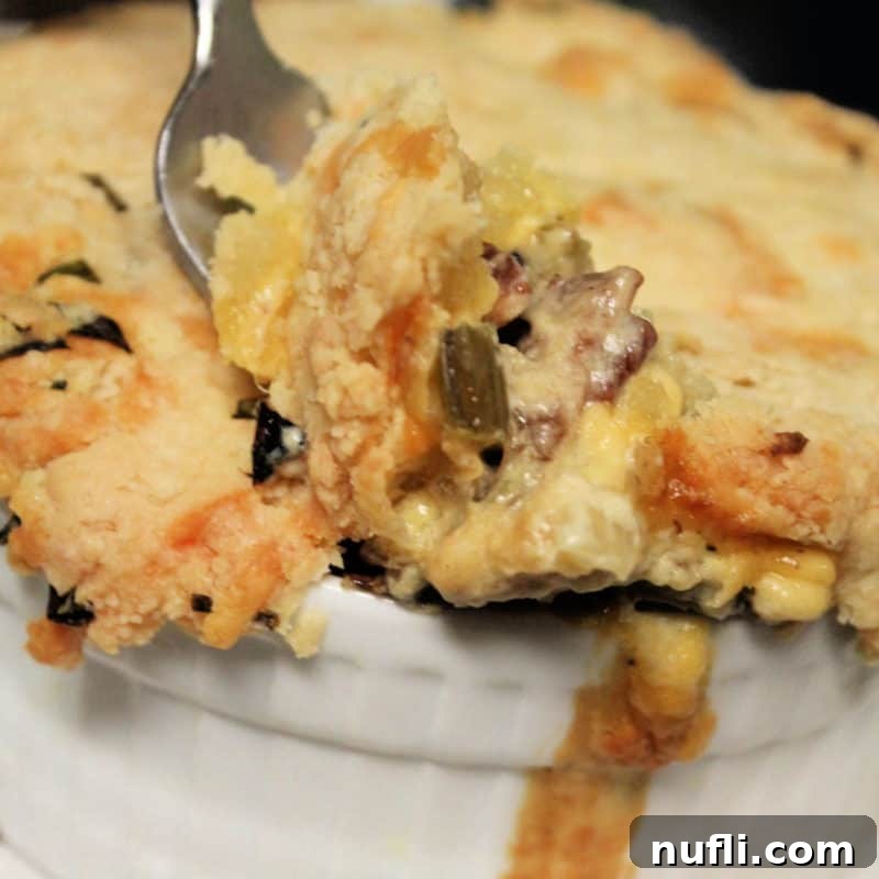 A fork scooping a generous portion of Bacon Pot Pie from a white ramekin.
