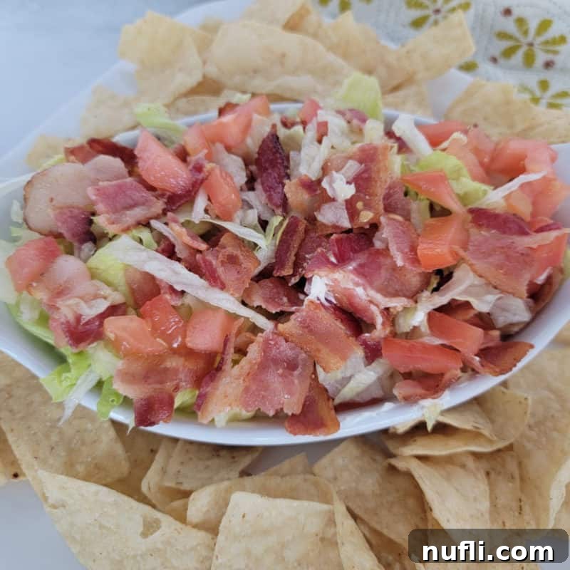 A fresh BLT Dip in a white bowl, ready to be scooped with tortilla chips.