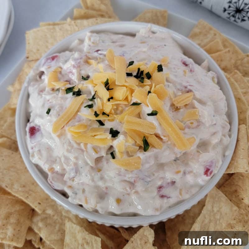 Fiesta Ranch Dip garnished with shredded cheddar cheese, surrounded by tortilla chips.