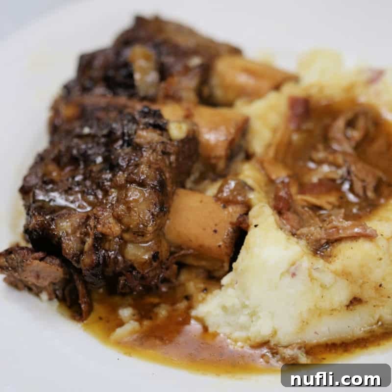 Guinness braised short ribs next to mashed potatoes on a white plate