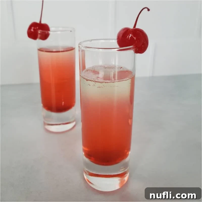 layered red cocktail garnished with cherries