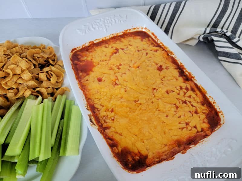 Franks Buffalo Dip in a white casserole dish with celery and corn chips