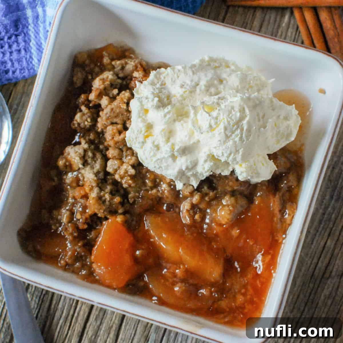 Apple spice dump cake in a white bowl with whipped cream