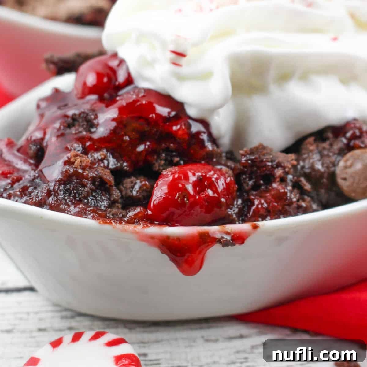 Chocolate Peppermint Cherry Dump Cake in a white bowl with whipped cream and peppermint candies