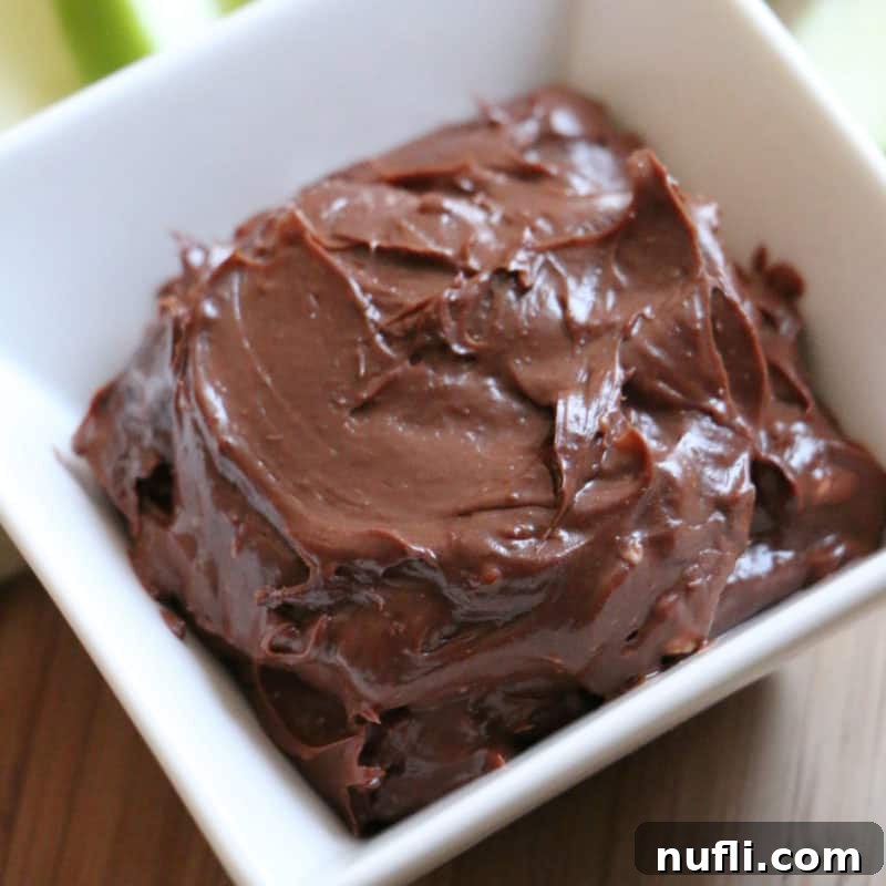 Decadent Edible Brownie Batter in a white bowl, accompanied by fresh apple slices for dipping