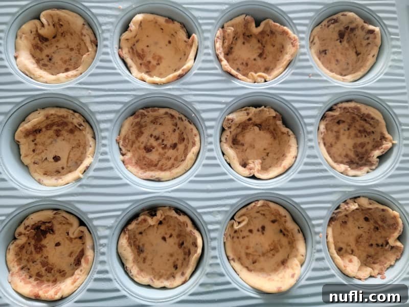 2-Ingredient Cinnamon Roll Apple Pie Bites 5 Cinnamon roll cups neatly arranged in a muffin tin, ready for filling.