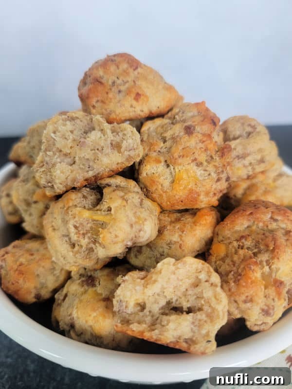 A white bowl brimming with golden Cheddar Bay Sausage Balls, ready for sharing at a party or gathering.