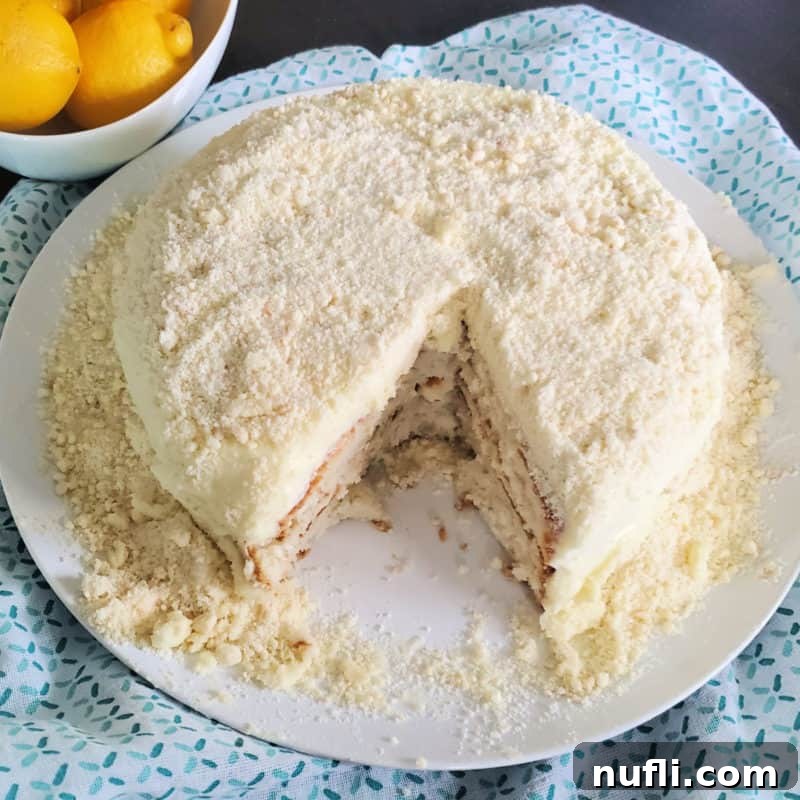 Lemon Cream Cake with a slice cut out of it next to a bowl of lemons 