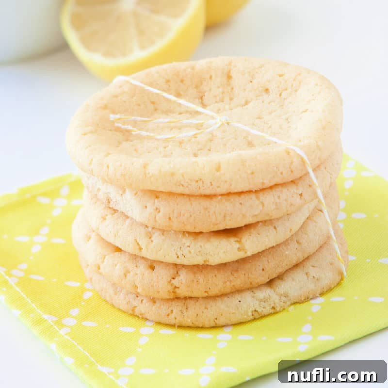 Lemon sugar cookies in a stack wrapped in twine on a yellow napkin with lemons in the background