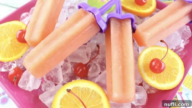 Bahama Mama Popsicles on a pink platter with oranges and cherries