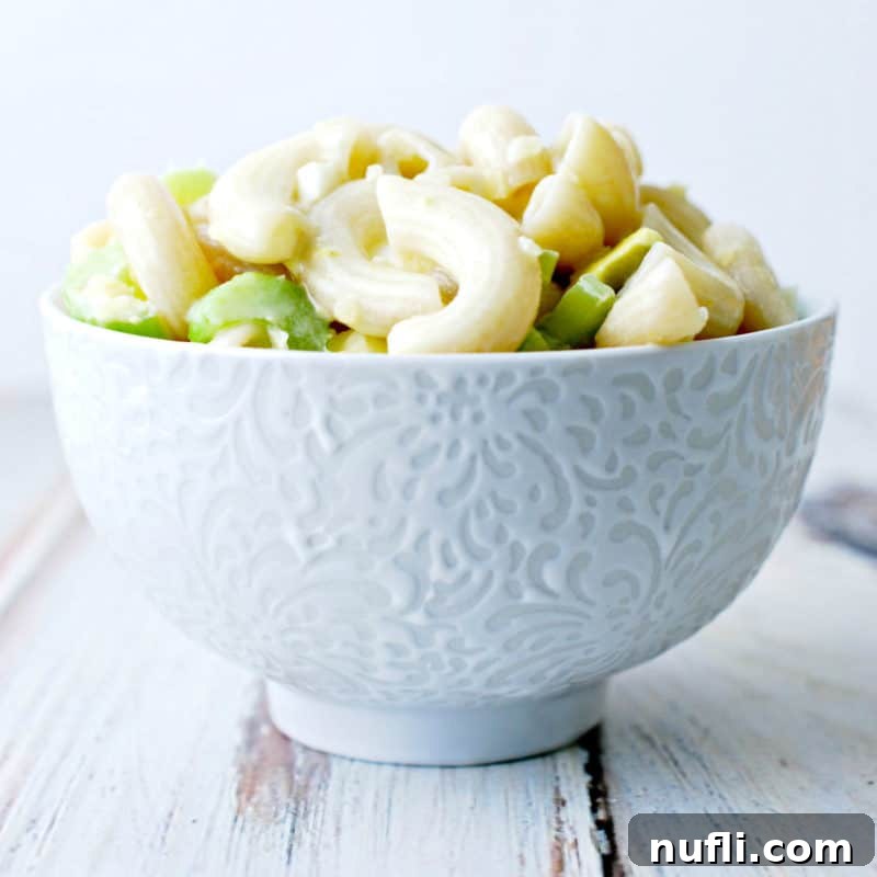 Classic Macaroni Salad with diced celery, served in a crisp white bowl, a refreshing side dish.